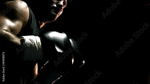 Muscular athlete practices boxing on a punching bag. Close up shot. photo