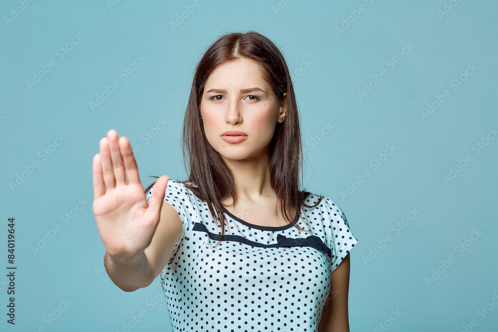 Young woman making stop gesture with her palm, on a blue Young woman making stop gesture with her palm, on a blue