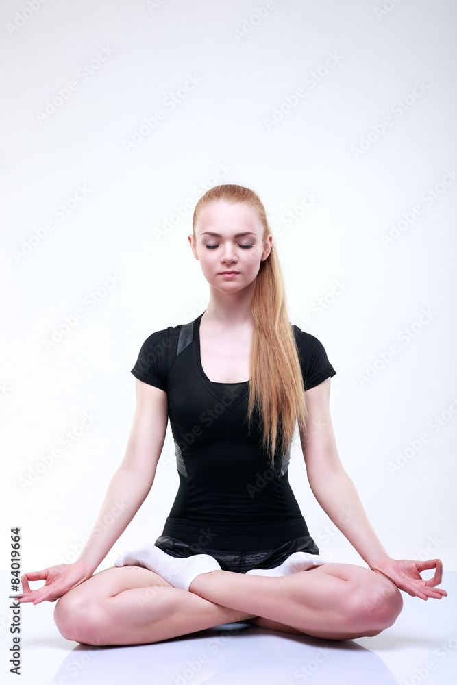 Beautiful young girl is engaged in a fitness, on a light-grey Beautiful young girl is engaged in a fitness, on a light-grey