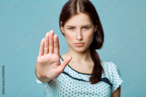 Lady making stop gesture with her palm, on a blue background
