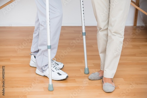 Doctor helping her patient walking with crutch