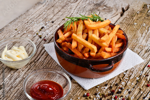 French fries in a bowl on a rustic wooden floor