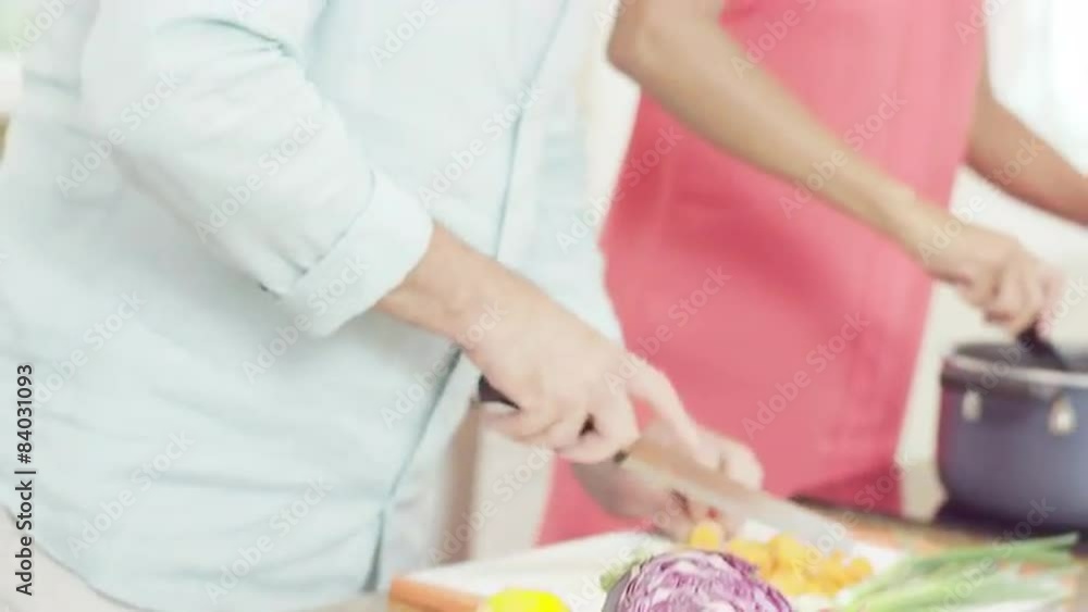 A man checks his tablet then goes back to helping is girlfriend prepare food in the kitchen A man checks his tablet then goes back to helping is girlfriend prepare food in the kitchen
