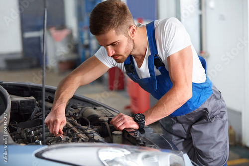 Portrait of a mechanic servicing a car at his workshop