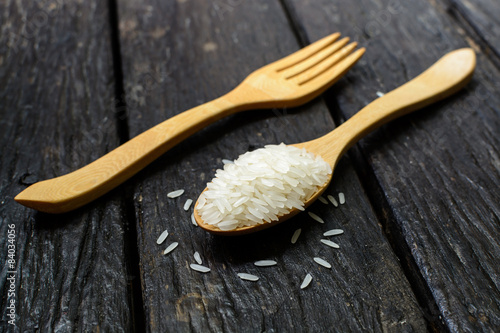 Rice in wooden spoon on old wooden
