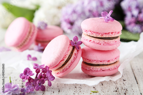 French pink macarons with lilac flowers on white wooden backgrou