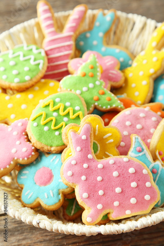 Colorful easter cookies in basket on grey wooden background
