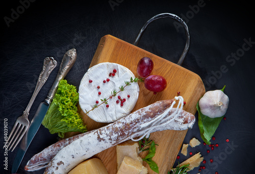 Various cheeses and salami on the wooden board photo