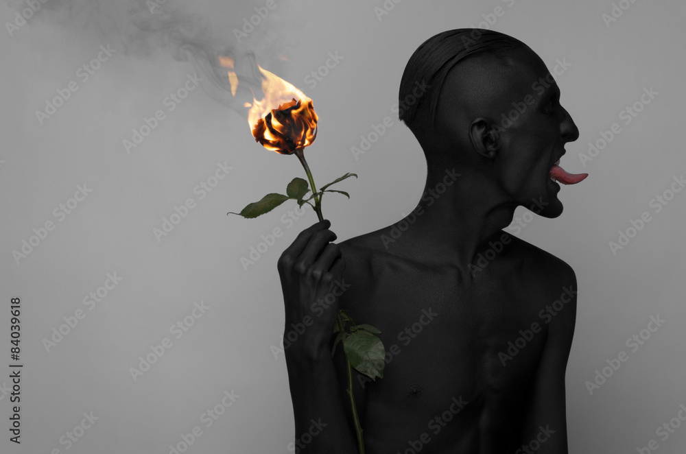 Fototapeta premium a man with black skin holding a burning rose, black death