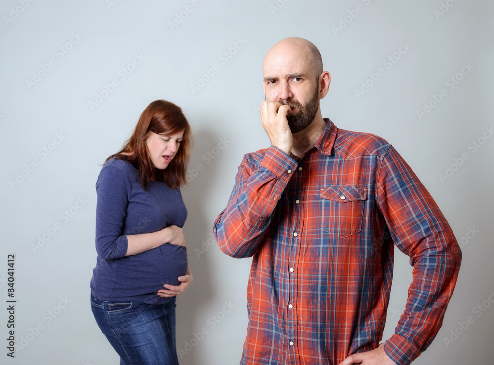Unsicherer Mann, schwangere Frau mit Schmerzen im Hintergrund - obrazy, fototapety, plakaty 