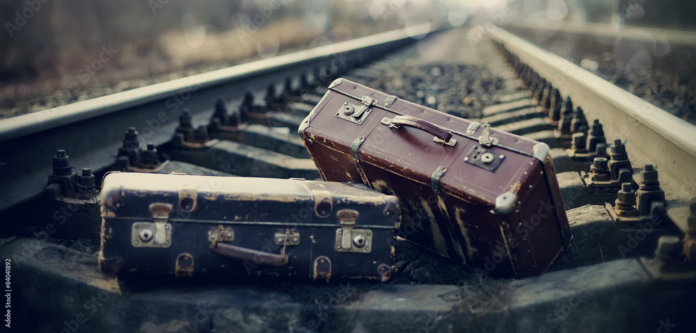 Two vintage suitcases lie on railway tracks.