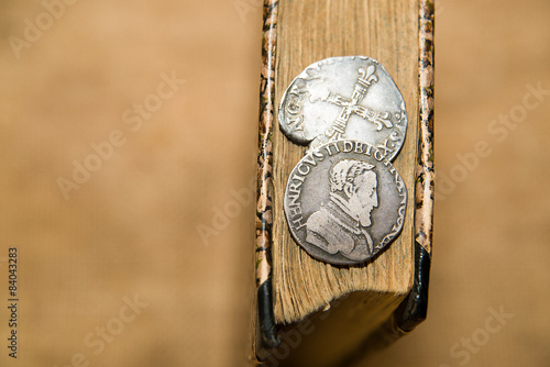 French old coin with a portrait of the King is on the book