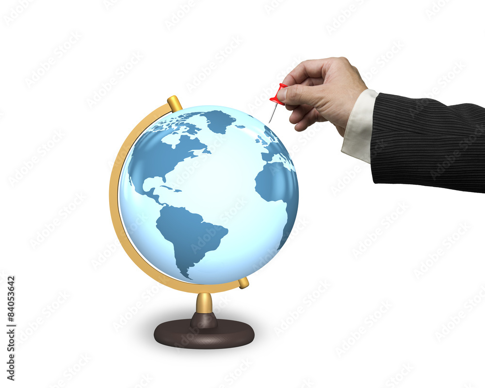 Male hand holding red pushpin with terrestrial globe Male hand holding red pushpin with terrestrial globe