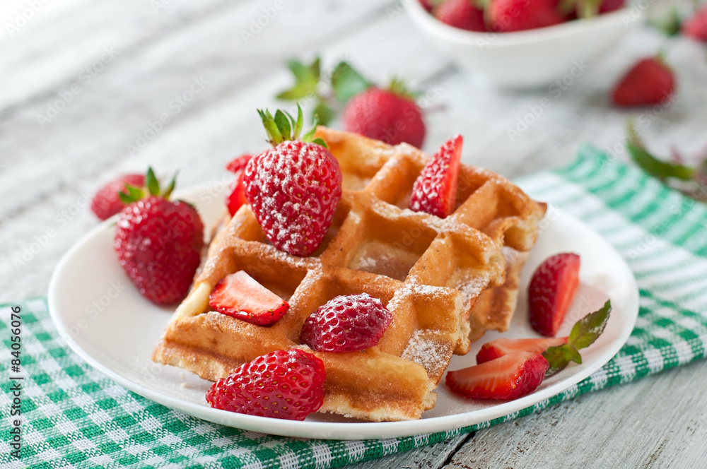 Belgium waffles with strawberries and mint on white plate Belgium waffles with strawberries and mint on white plate