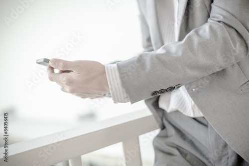 Young businessman using a phone sitting on the stairs