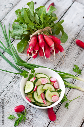 Fresh salad of cucumbers and radishes in a white bowl