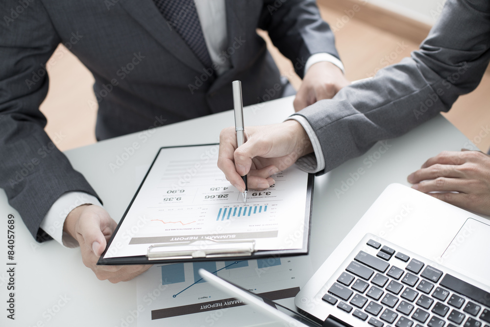 Two businessmen looking at report and having a discussion in off Two businessmen looking at report and having a discussion in off