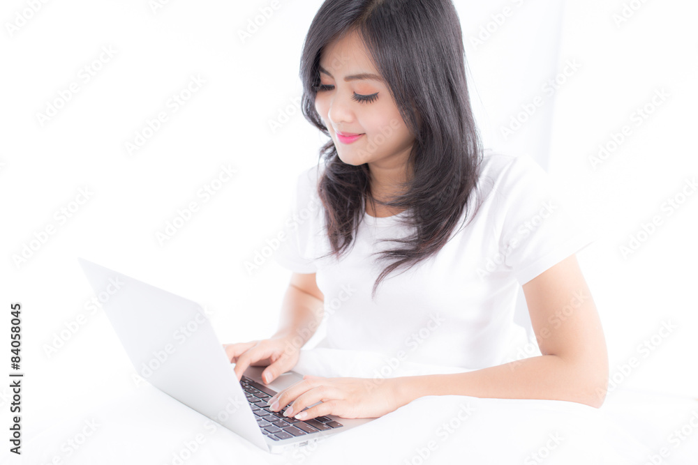 Smiling woman using a laptop while lying on her bed Smiling woman using a laptop while lying on her bed