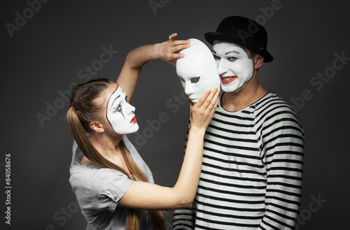 Obraz na płótnie Female mime holding a mask in front of male mime's face