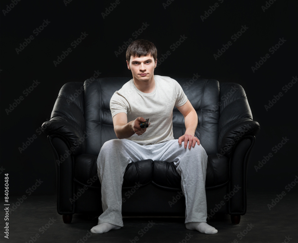Young sports fan watching football broadcast sitting on a sofa