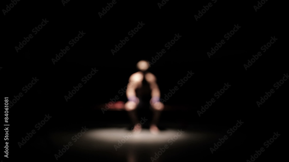 Muscular athlete sits on a bench anticipating competition. Wide shot. Muscular athlete sits on a bench anticipating competition. Wide shot.
