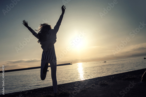 Girl jumping over sunrise.