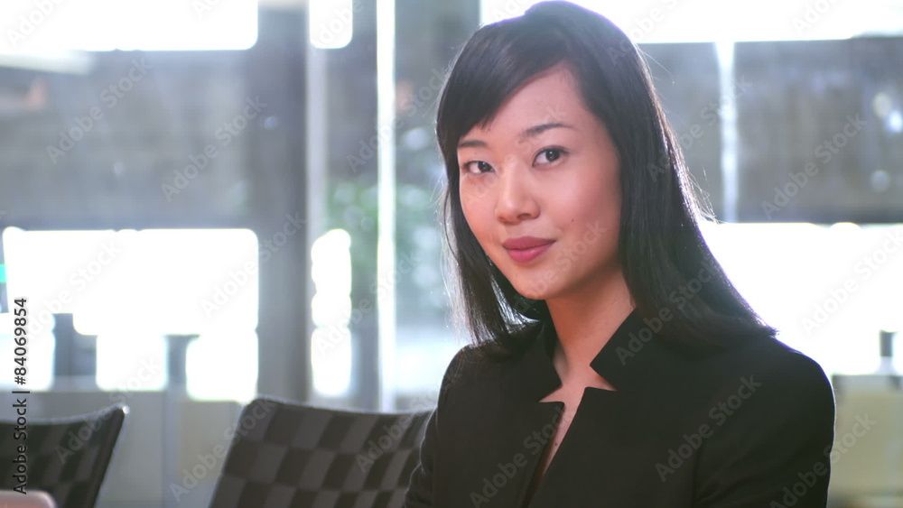 An attractive young businesswoman works alone and then smiles at the camera. An attractive young businesswoman works alone and then smiles at the camera.
