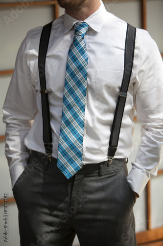 Obraz na plátně Young man wearing suspenders and colorful tie with hands in pock