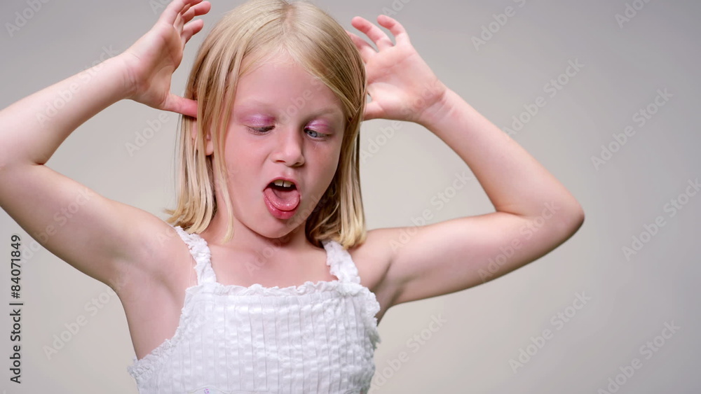 Young blonde girl pulls a funny face against a white background Young blonde girl pulls a funny face against a white background