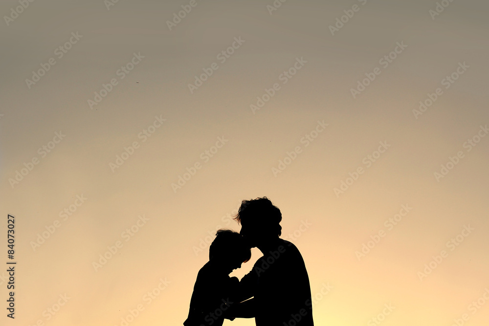 Silhouette of Father Kissing Young Child on Forehead
