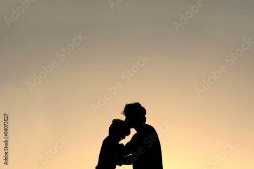 Silhouette of Father Kissing Young Child on Forehead