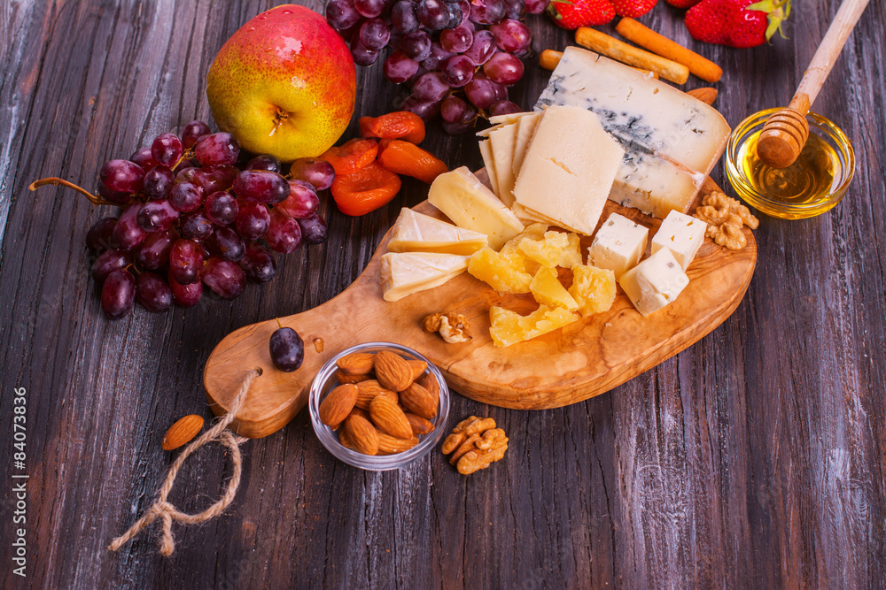 Different types of cheese with fruits, berries, honey and nuts