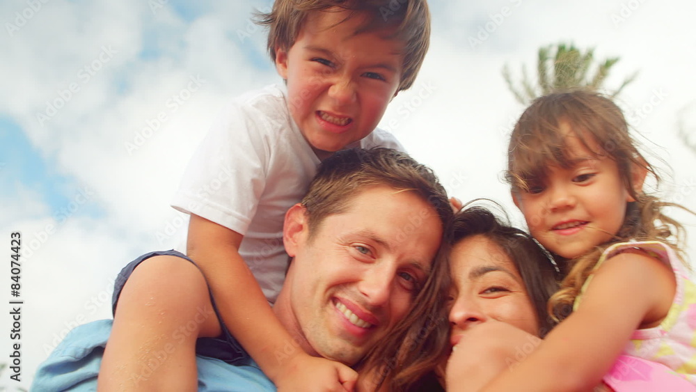 A mother and father hold their son and daughter on their shoulders at the beach A mother and father hold their son and daughter on their shoulders at the beach