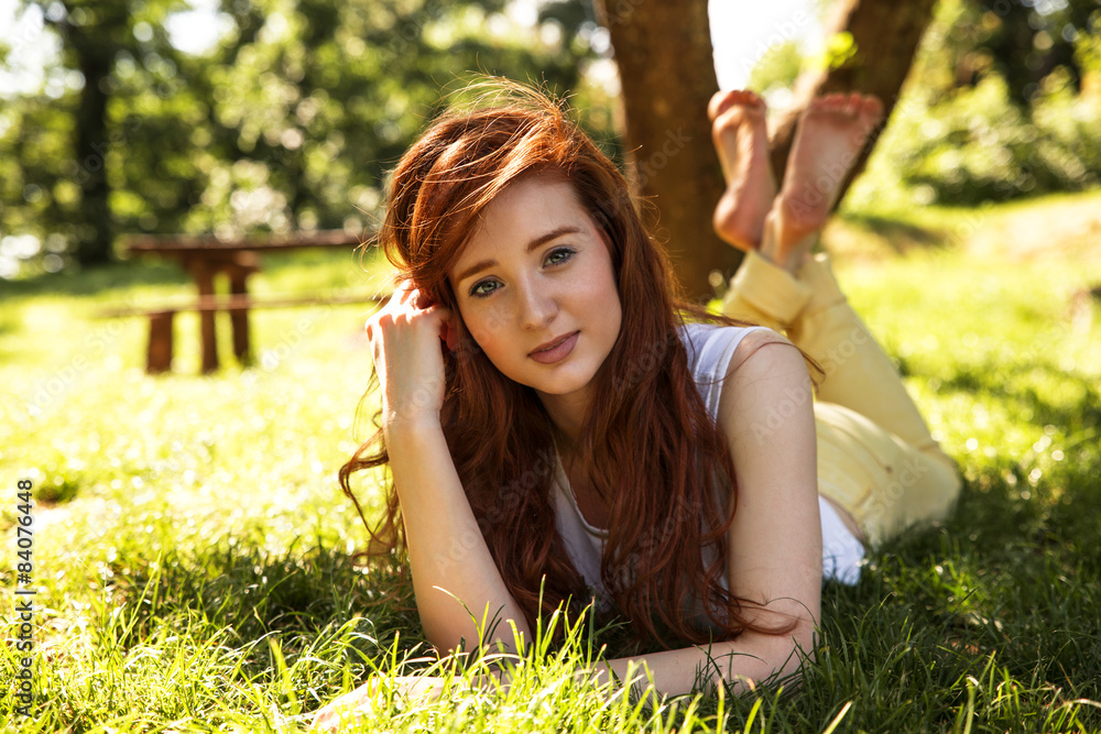 Beautiful red hair woman lying on grass at the park