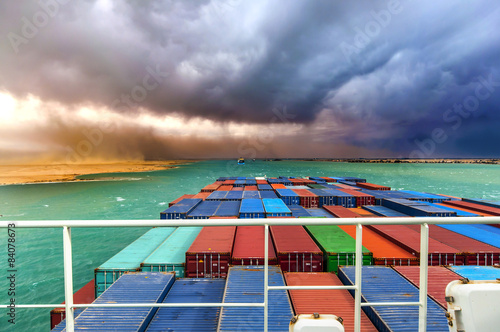 Suez Canal, Egypt. Container ship going through desert storm