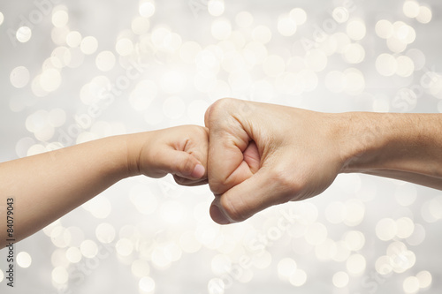 father and son punching fists on christmas lights background