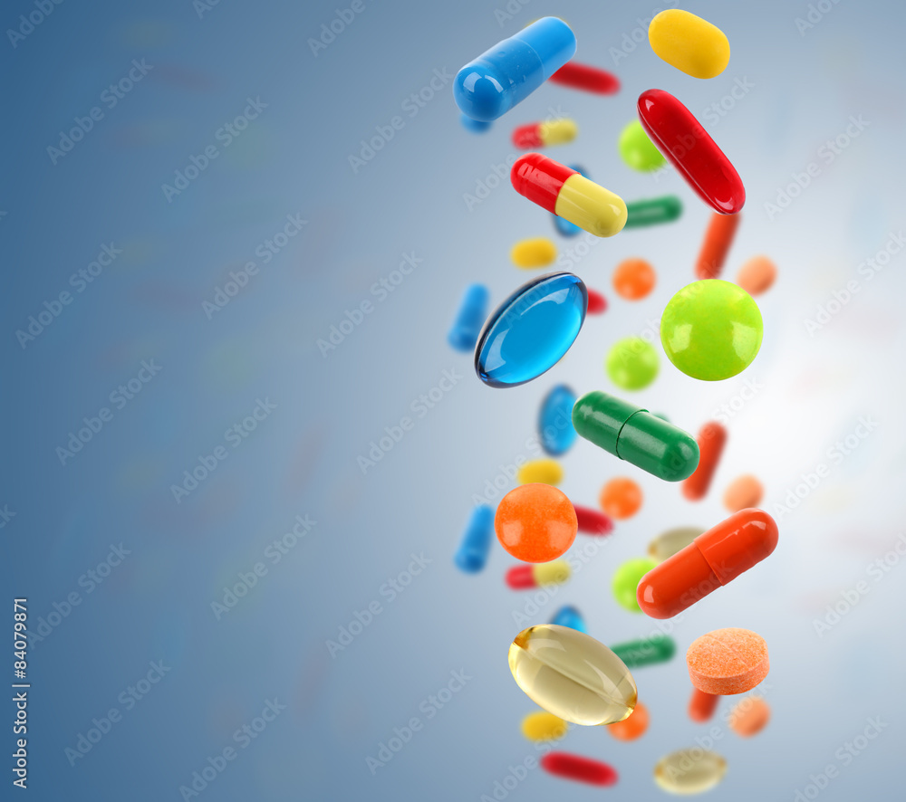 Falling colorful medical pills on blue background Falling colorful medical pills on blue background