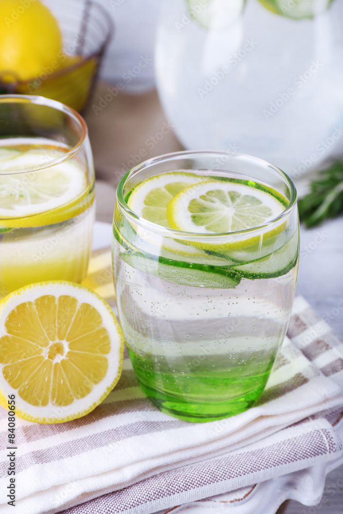 Fresh water with lemon and cucumber in glassware on wooden table, closeup Fresh water with lemon and cucumber in glassware on wooden table, closeup