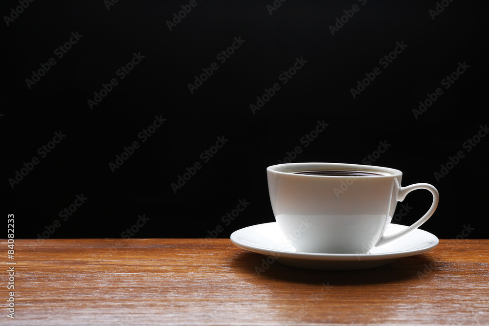 Cup of coffee on wooden table on black background Cup of coffee on wooden table on black background