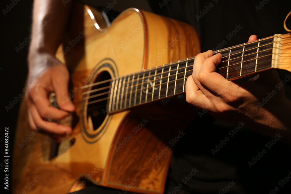 Fototapeta premium Young man playing on acoustic guitar close up