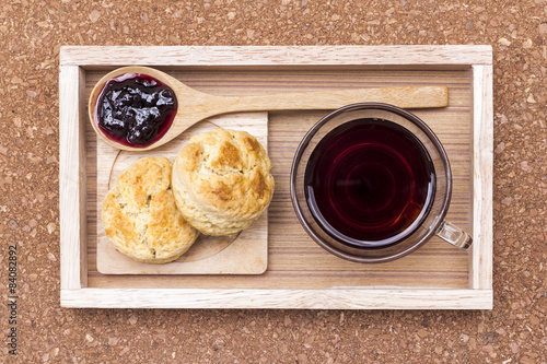 Scone,jam,coffee on wooden tray.