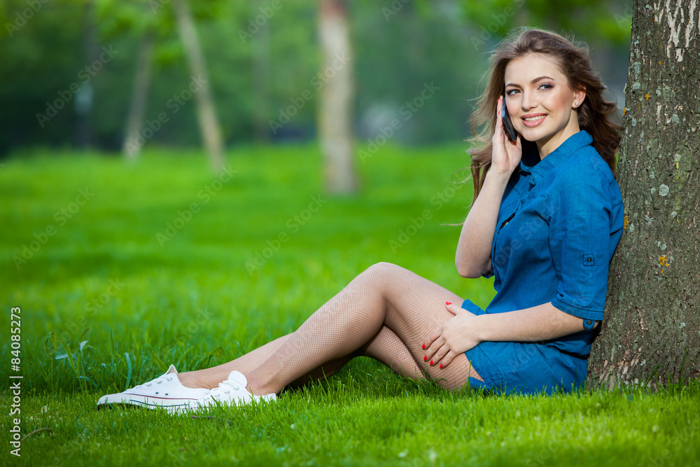 Pretty young caucasian woman sitting outside under a tree Pretty young caucasian woman sitting outside under a tree