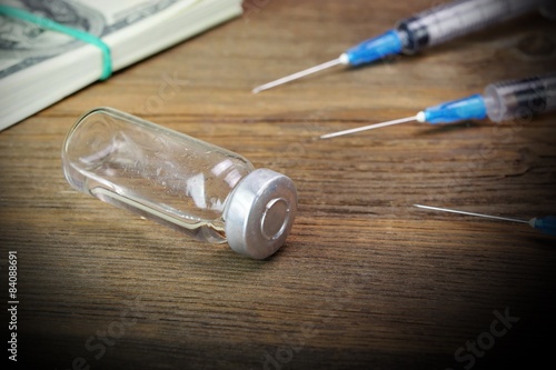 Money Wad, Syringe And Vial On Rough Wood Table