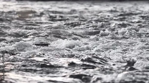 Close up abstract view of rushing water flowing down the river in winter, in slow motion