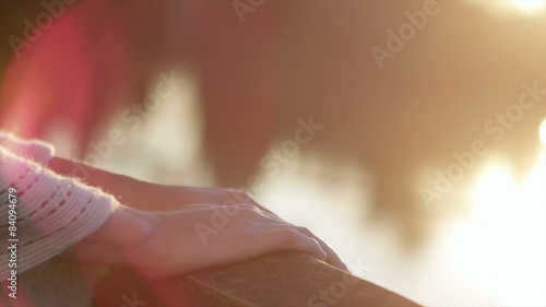 Wallpaper Mural Close up of a young woman's hands on a banister next to lake with lens flare Torontodigital.ca