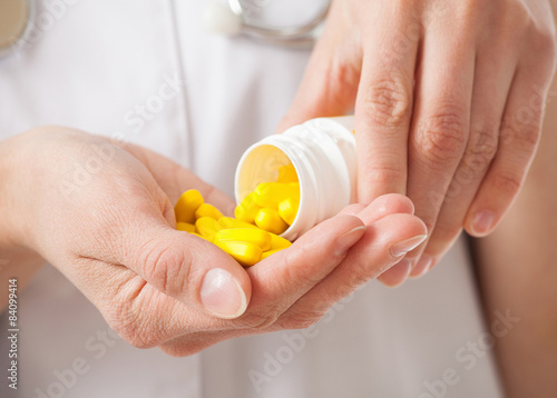 Doctor's pouring yellow tablets in the palm photo