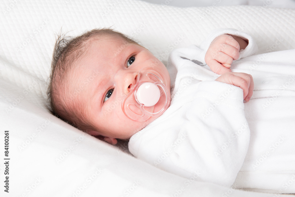 Adorable baby wearing a white clothe with a soother Adorable baby wearing a white clothe with a soother