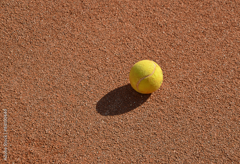 one yellow tennis ball on the clay tennis field