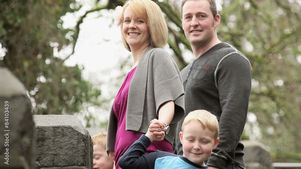 A young family holds hands and walks through a park A young family holds hands and walks through a park
