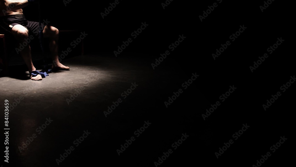 Athlete sitting on a bench prepares his hands by wrapping them. Wide shot. Athlete sitting on a bench prepares his hands by wrapping them. Wide shot.